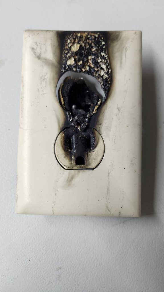 Scorched electrical outlet with burn damage around the receptacle